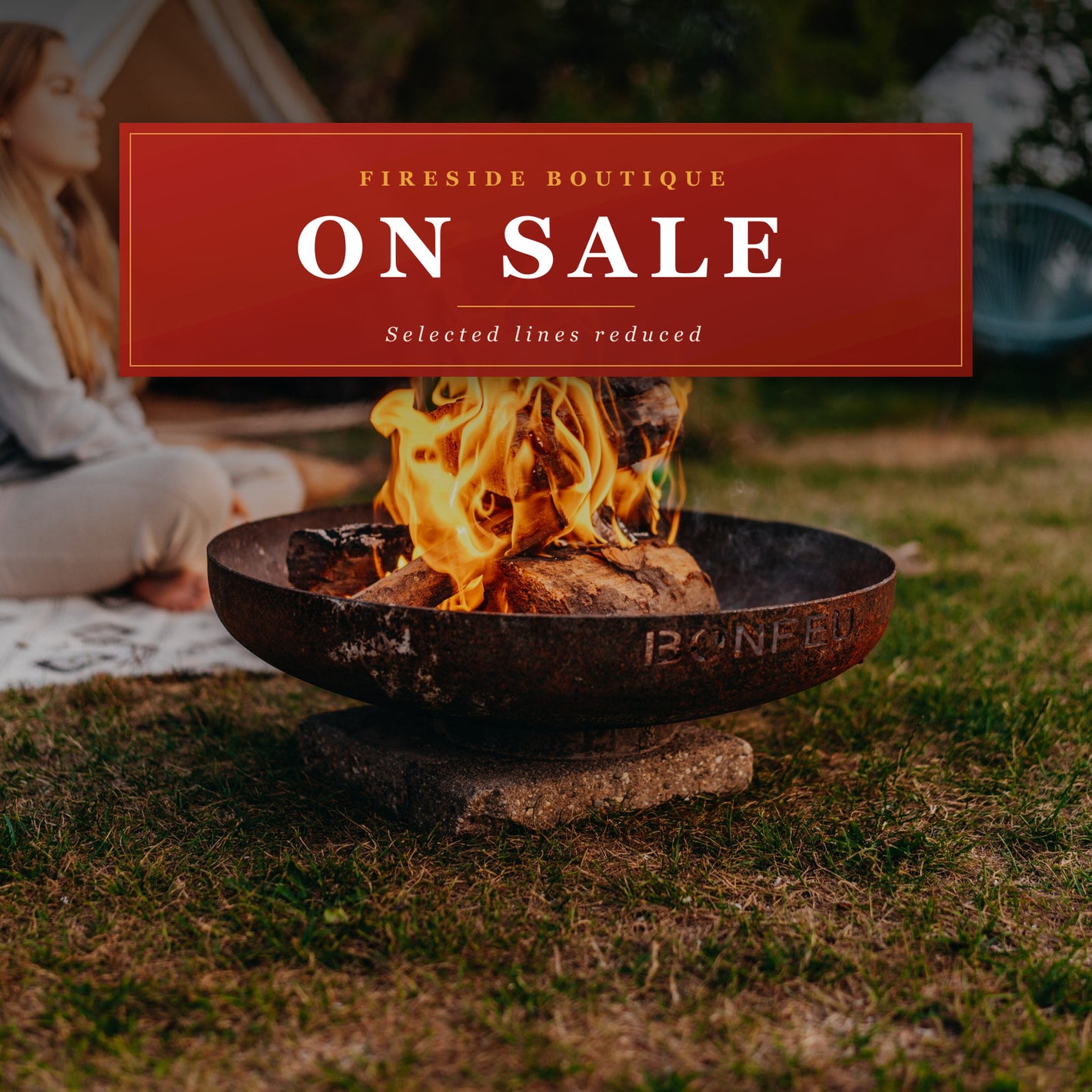On Sale at Fireside Boutique: a lit BonFeu BonBowl corten steel fire pit in a garden at dusk